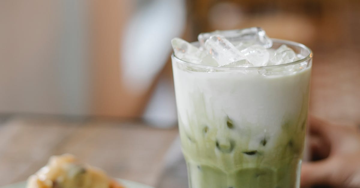 Glass of tasty refreshing matcha latte served on table with yummy pie slice in cafe