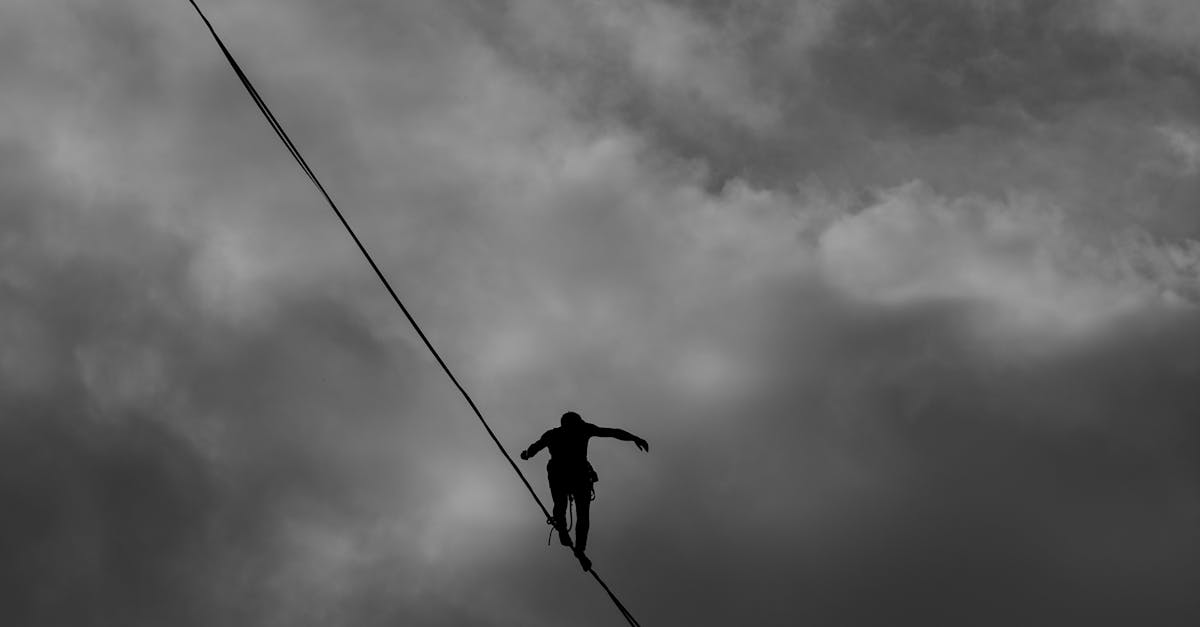 Low Angle Photo Grayscale of Person Tightrope Walking