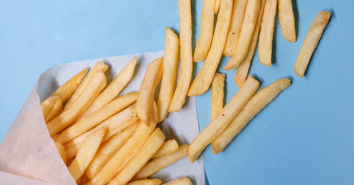 Fried potatoes in paper on blue background