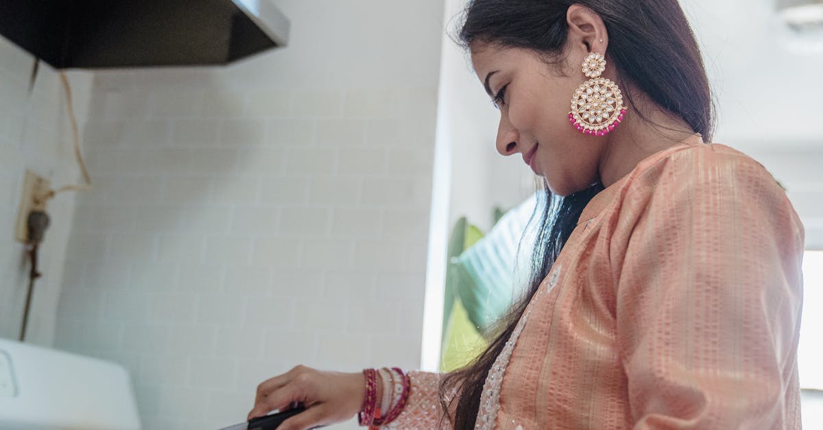 Woman in Orange and White Floral Dress Holding Black Smartphone