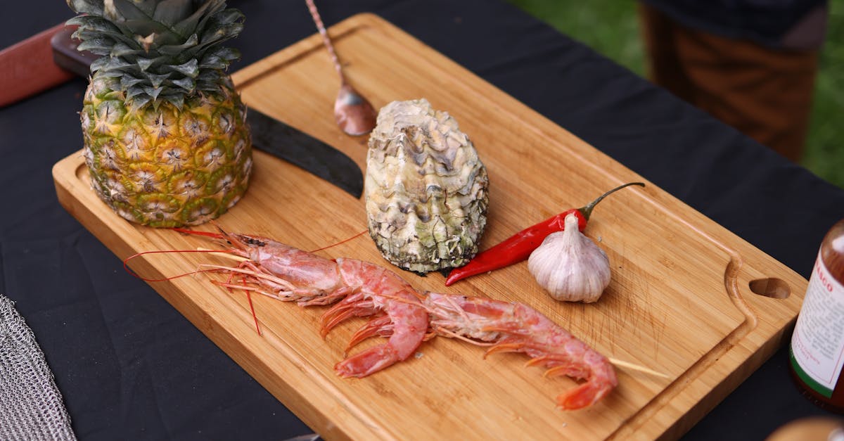 A cutting board with pineapples, shrimp and other ingredients