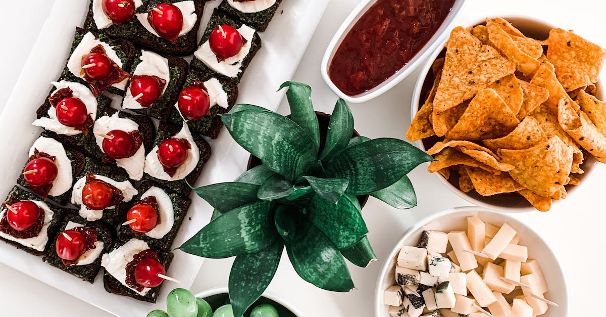 Top view of tasty canapes with cherry tomatoes near bowl with grapes and barbecue sauce