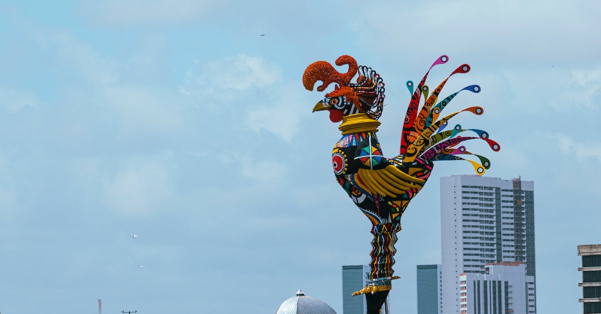 A colorful statue of a rooster in a park