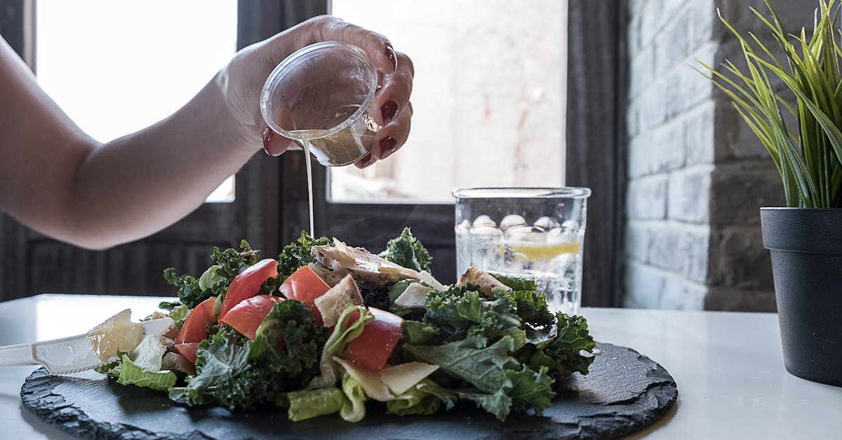 Person Pouring Dip on Vegetable Salad