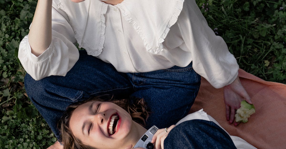 Two women are laying on the grass and smiling