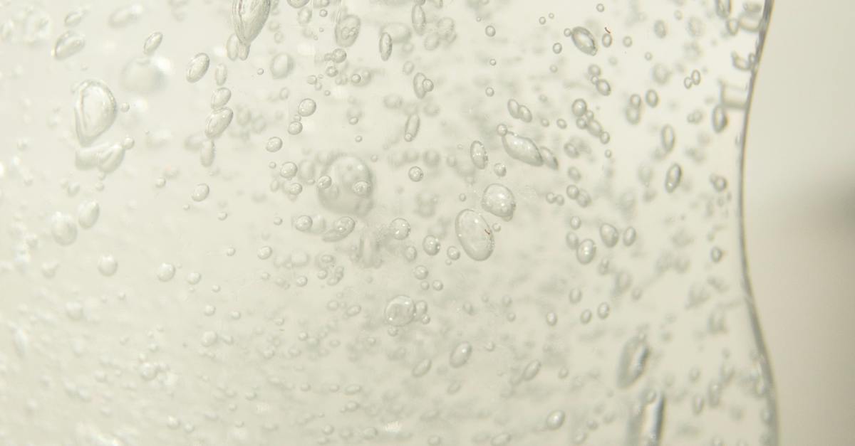 Glass jar with water with bubbles against white background