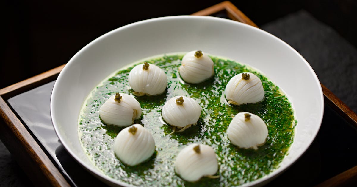 A bowl of soup with scallops and green herbs