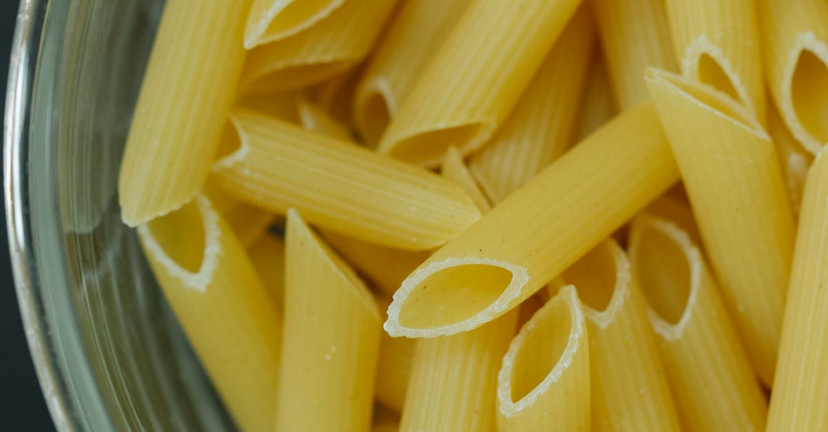 From above of traditional Italian dried uncooked penne pasta in glass bowl on table