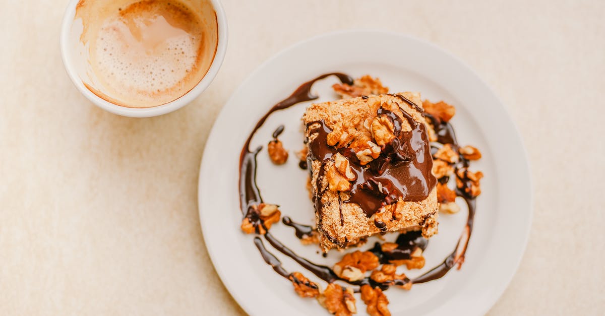 Top view of delicious homemade dessert with chocolate glaze topped with walnuts and cup of fresh cappuccino with froth