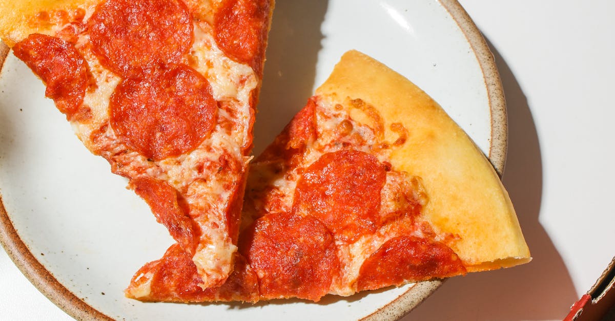 Person Holding A Slice Of Pizza On A Plate