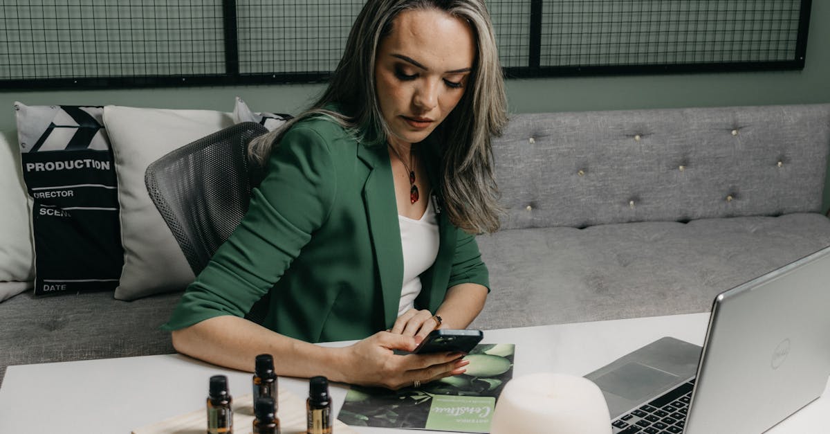 A woman sitting at a desk with a laptop and a bottle of essential oils