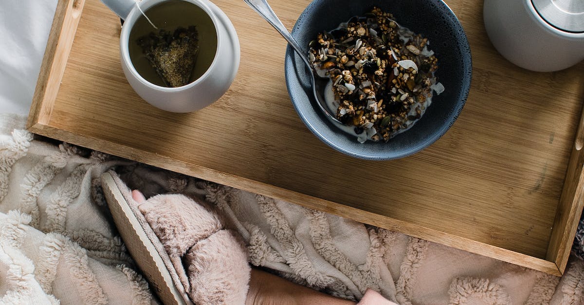 Woman sitting on bed with breakfast on tray