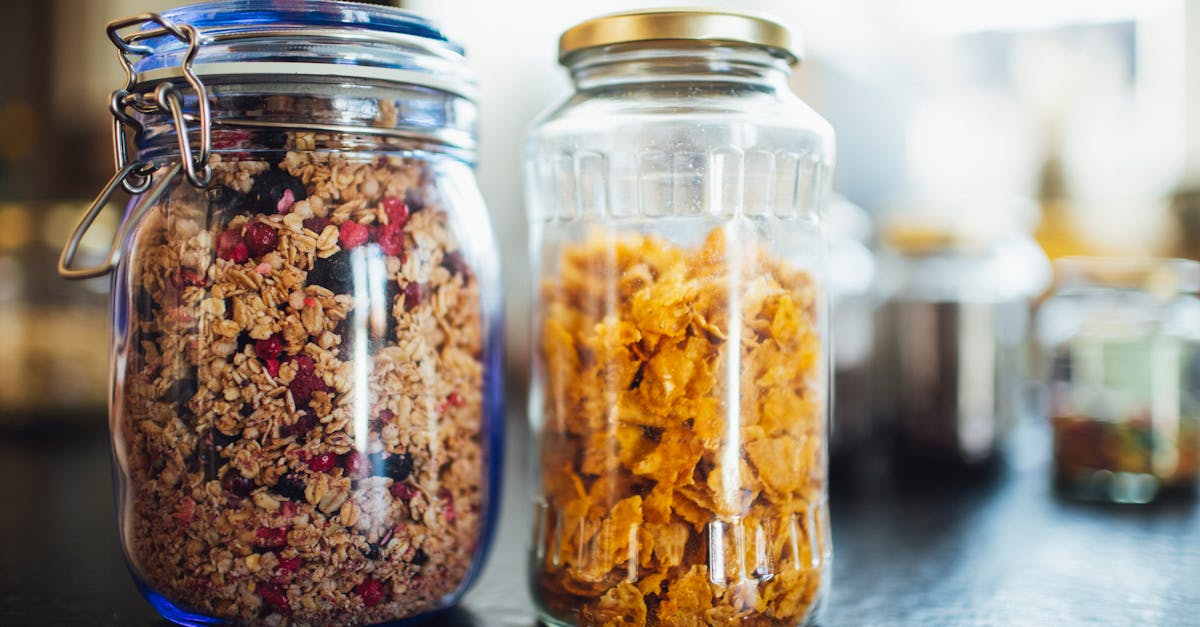 Glass jars with healthy cornflakes and muesli placed  on table in kitchen