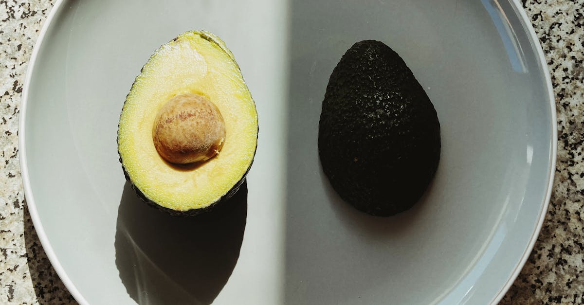 Top view of halves of fresh avocado placed on gray plate with half in shadow