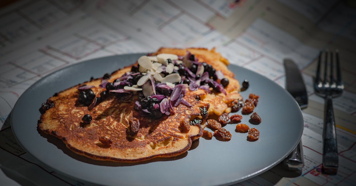 Brown Pancake With Brown Purple White Nut on Grey Round Plate Beside Silver Knife and Fork