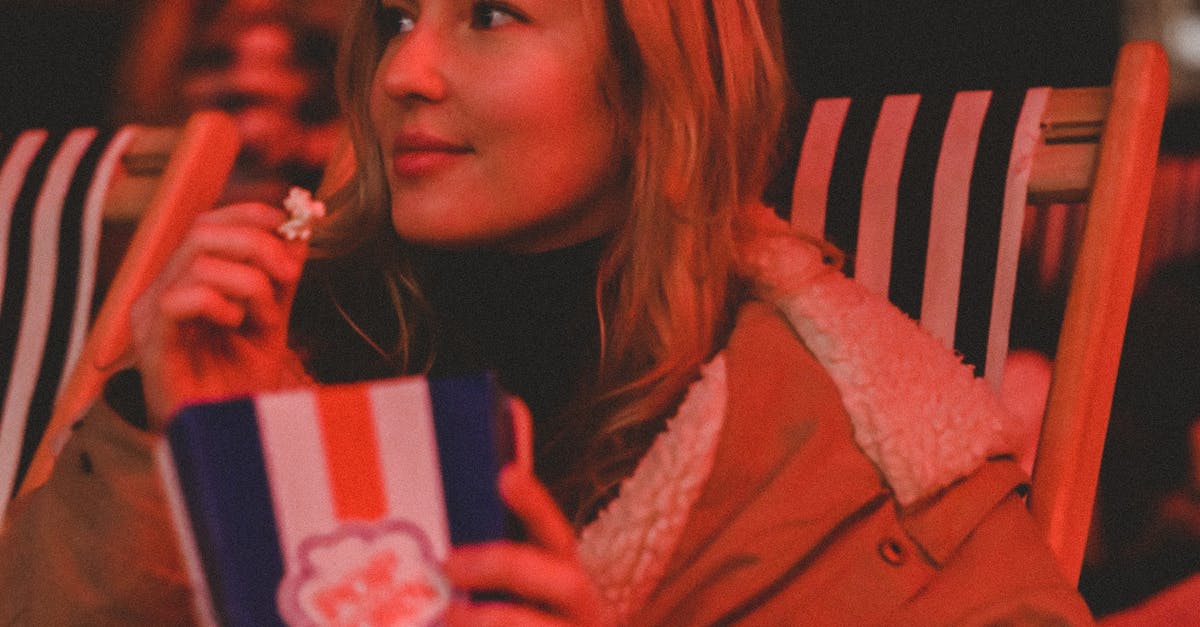 A woman sitting in a chair with a popcorn and a drink