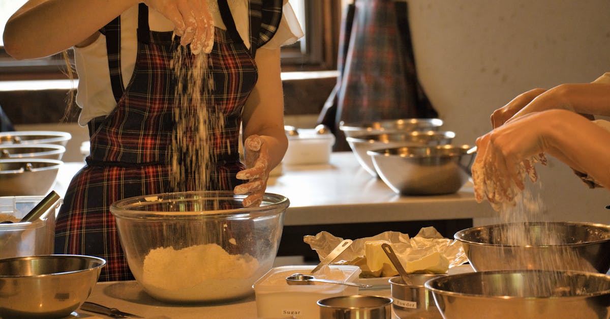 Two women in aprons are mixing dough in a kitchen