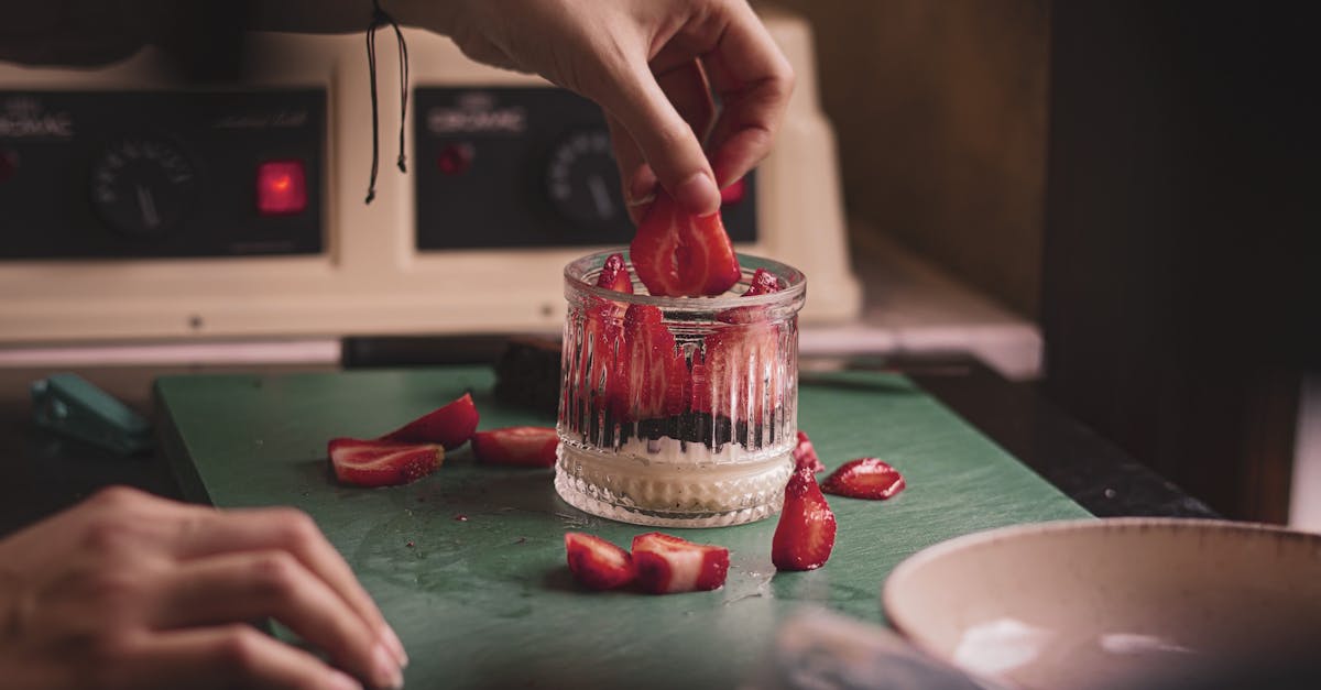 A person is cutting strawberries on a cutting board