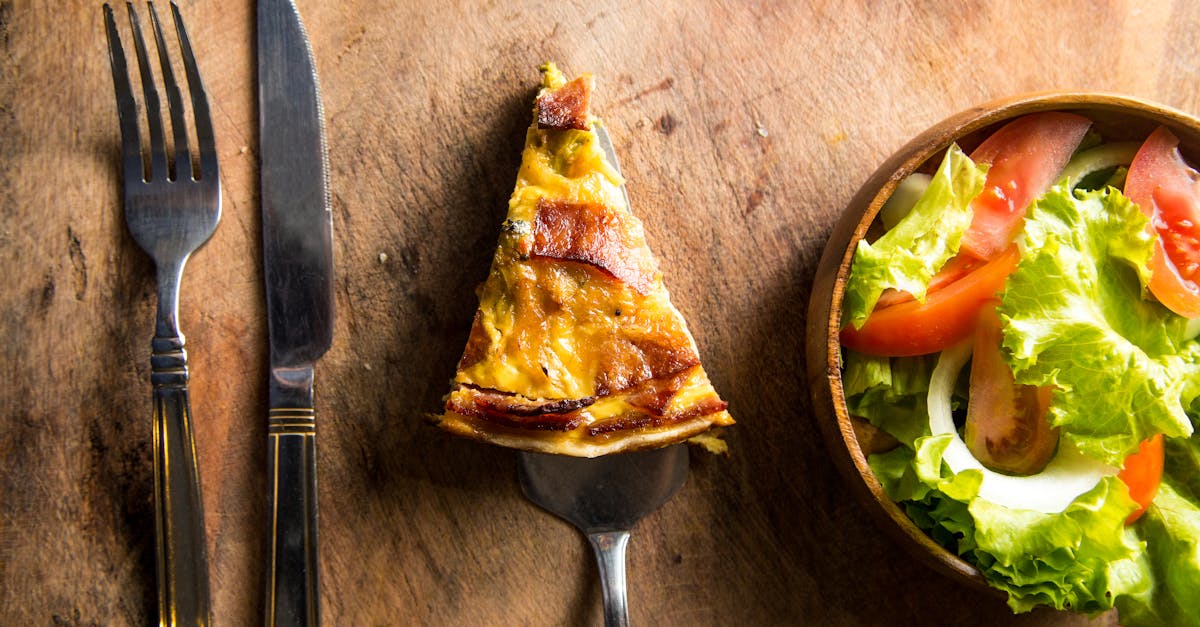 Slice of Pizza Beside Fork and Knife