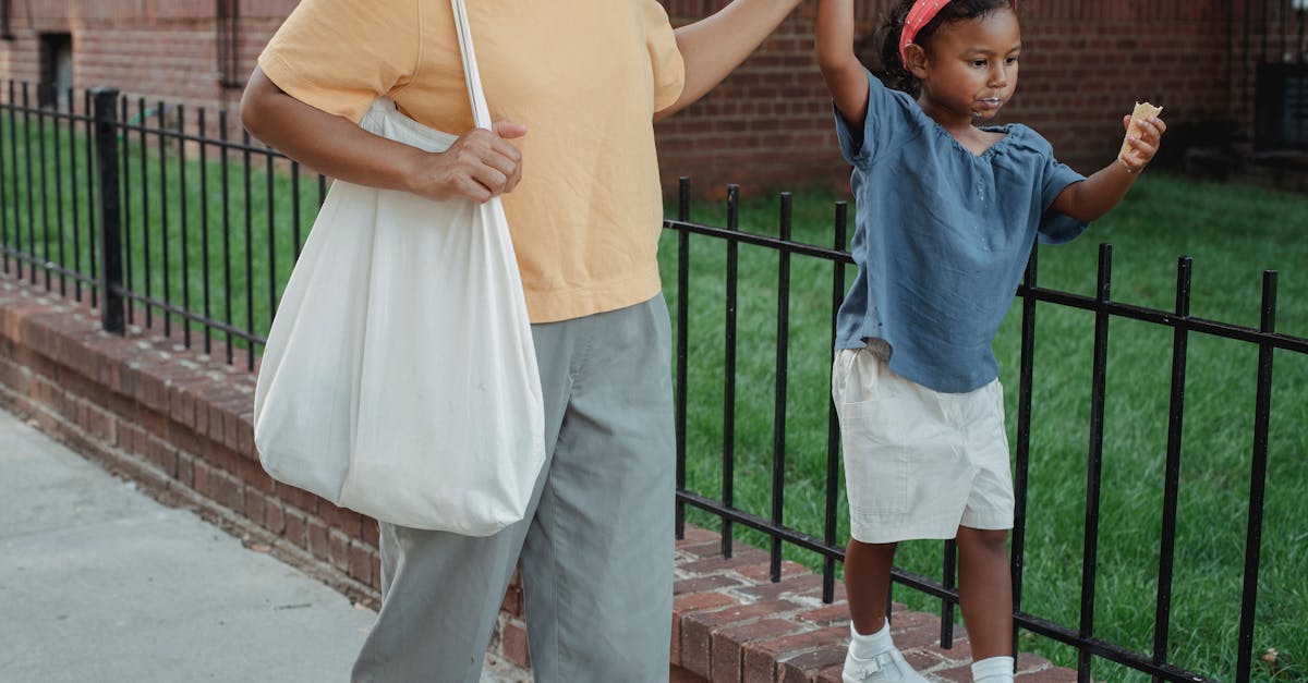 Calm Asian girl in casual clothes with ice cream in hand walking with unrecognizable woman on street in city in daytime