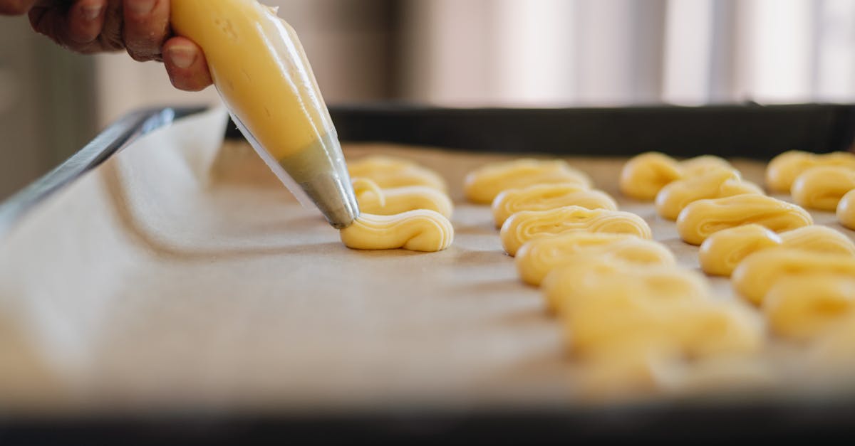 Close-up of Person Using a Pastry Bag to Squeeze Pastry onto a Tray with Parchment Paper 