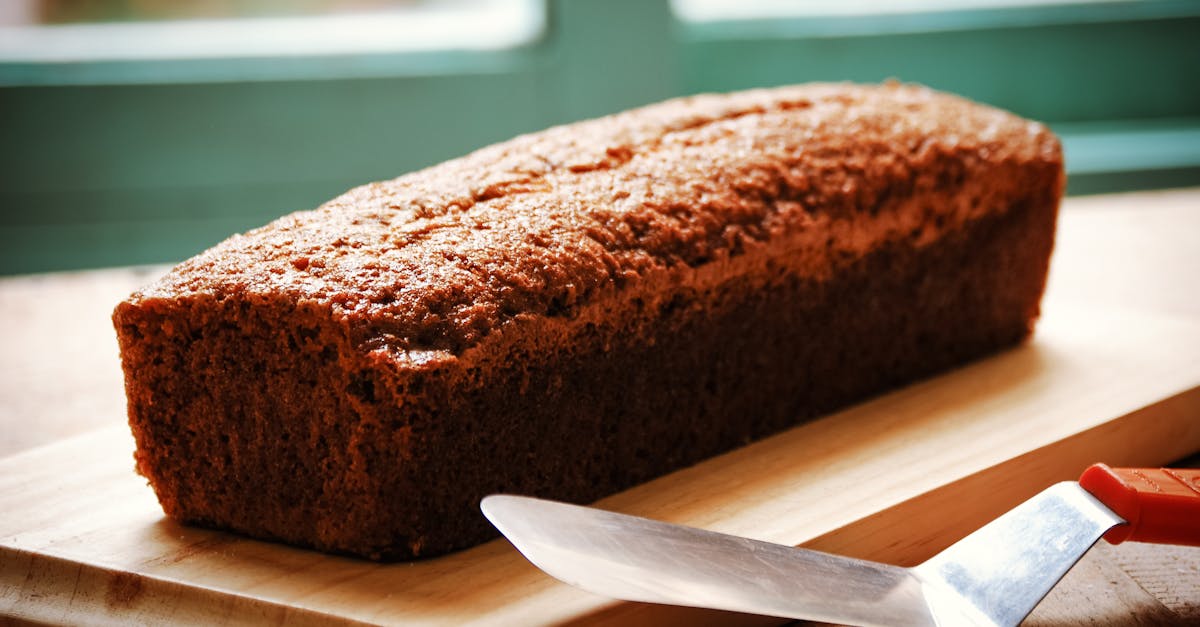 High angle of whole crispy fresh baked banana bread served on wooden cutting board and placed on table with spatula