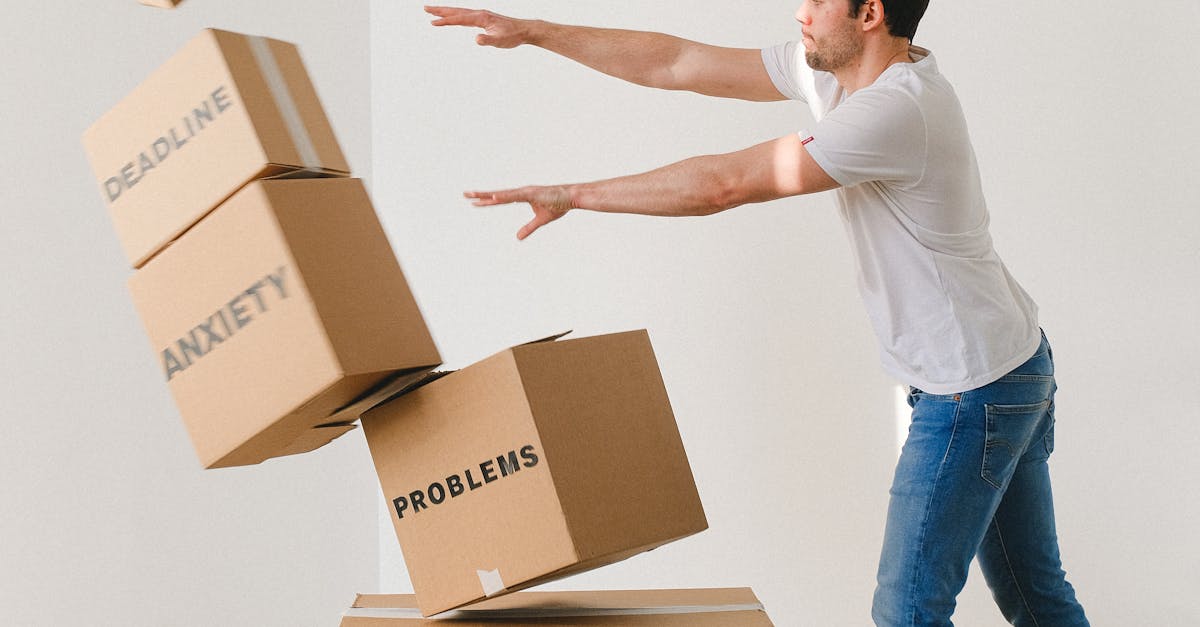 Full body of young man in sneakers and jeans pushing and falling boxes saying Work Problems Anxiety Stress and Deadline while fighting with problems