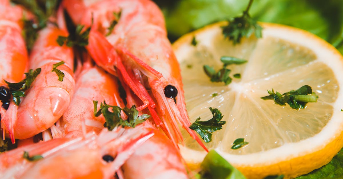 Closeup of whole yummy shrimps with fresh lemon circle and parsley pieces on lettuce leaf on blurred background