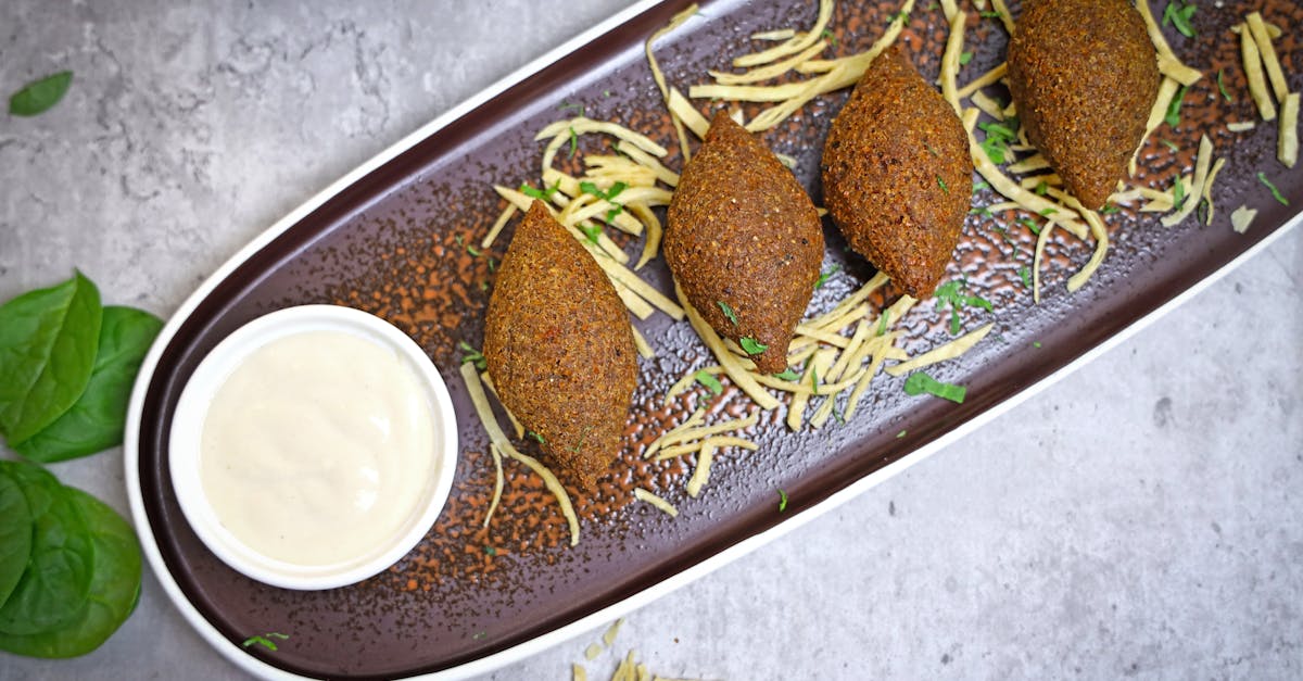 A plate with three meatballs and a dipping sauce