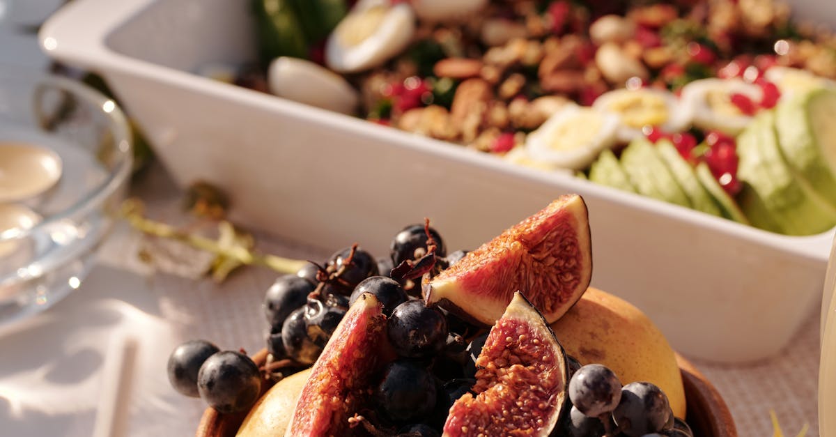 High angle of ceramic plate with fresh fruits and berries on table with various snacks