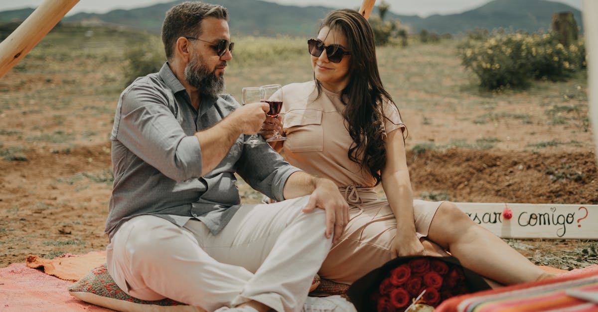 A couple sitting on a blanket in front of a tent